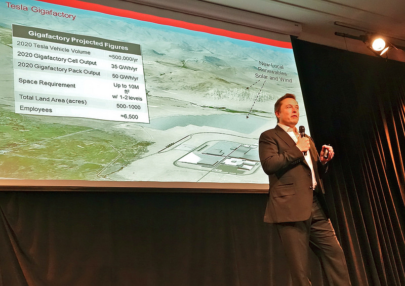 Elon Musk présentant la giga-usine "Gigafactory" en 2014 (photo par Steve Jurvetson diffusée sous le titre "Elon Musk describing the Tesla Gigafactory" sur Flickr en licence Creative Commons https://creativecommons.org/licenses/by/2.0/)