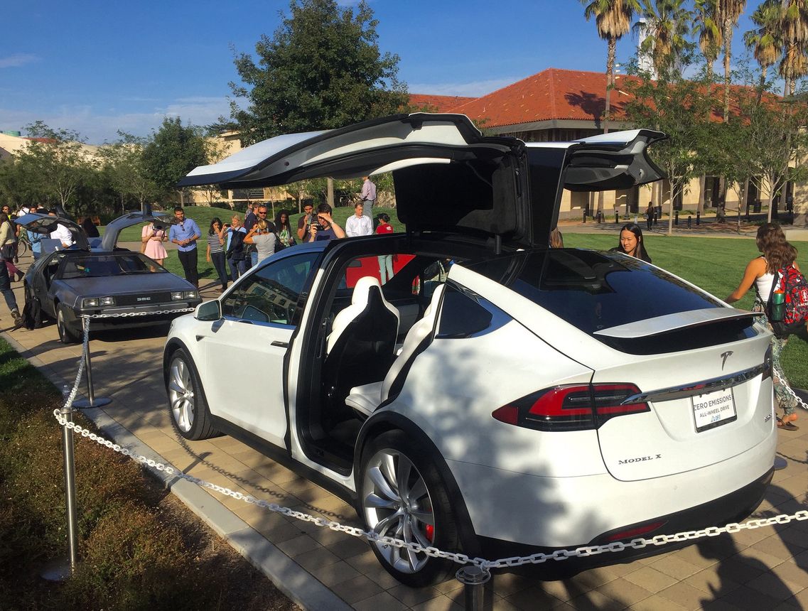 Un SUV Tesla Model X dont les portes "faucon" sont partagées avec la DeLorean du film "Retour vers le Futur" (photo par Steve Jurvetson diffusée sous le titre "Model X vs. DeLorean "The Doors that Go Like This"" sur Flickr en licence Creative Commons https://creativecommons.org/licenses/by/2.0/)
