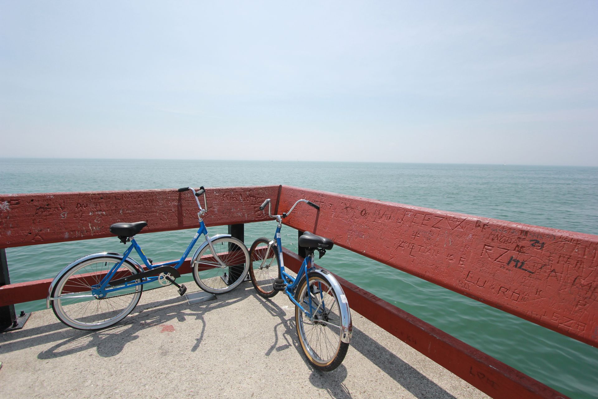 La gestion de l'autonomie du smartphone est indispensable pour garer ses deux vélos bleus contre une rambarde au bord de la mer !